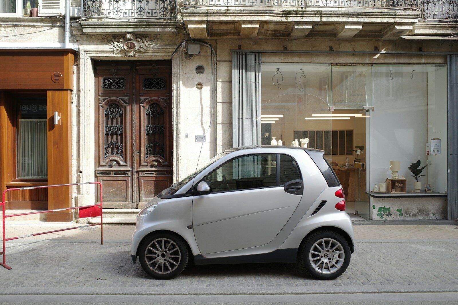 A silver smart car parked on a city street.